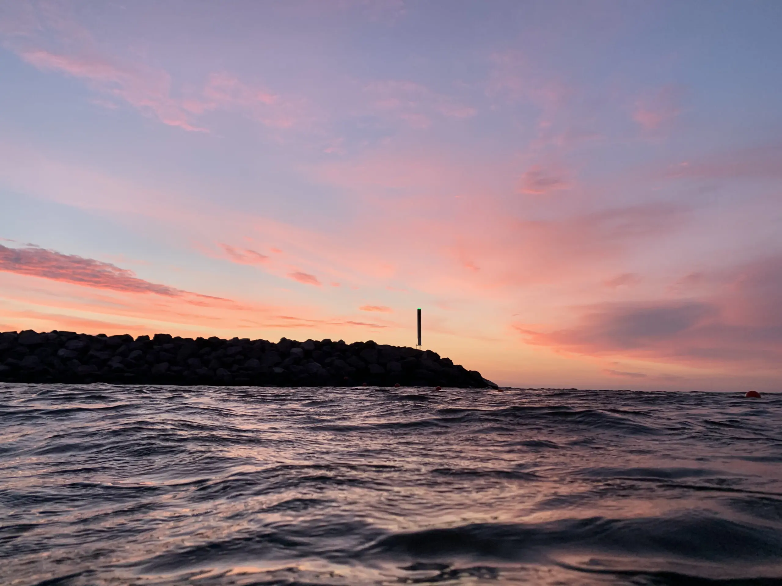 Smuk lyserød solnedgang over havet ved en stensætning nær Hvisker med heste.
