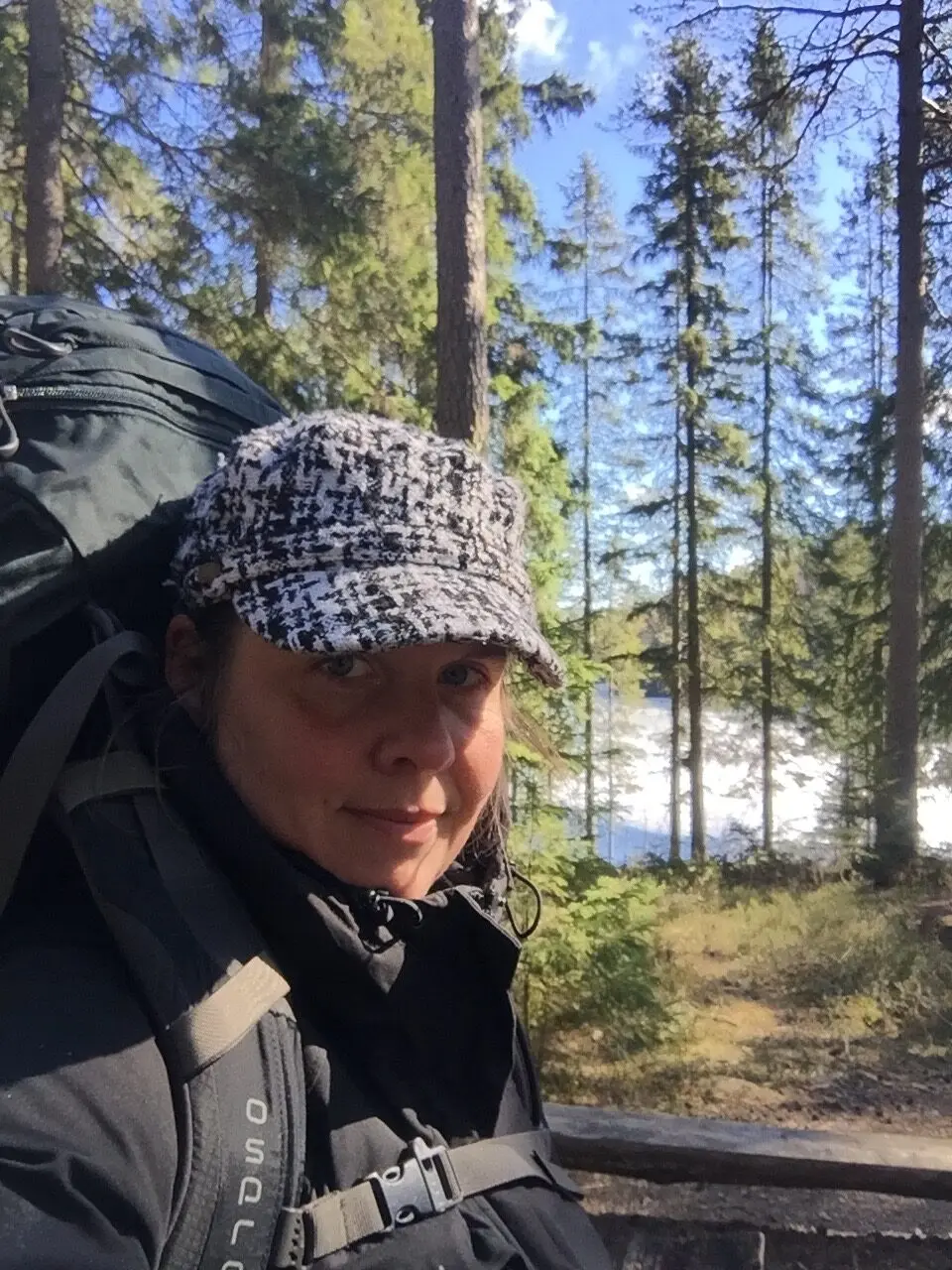 Manja fra Hvisker med heste på vandretur i skoven med rygsæk og kasket.