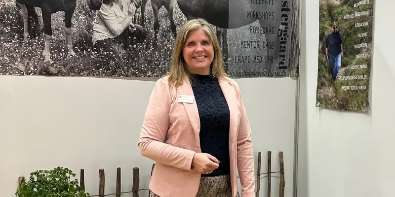Kvinde foran banner med uddannelser hos Hvisker med heste til foredrag og workshops.